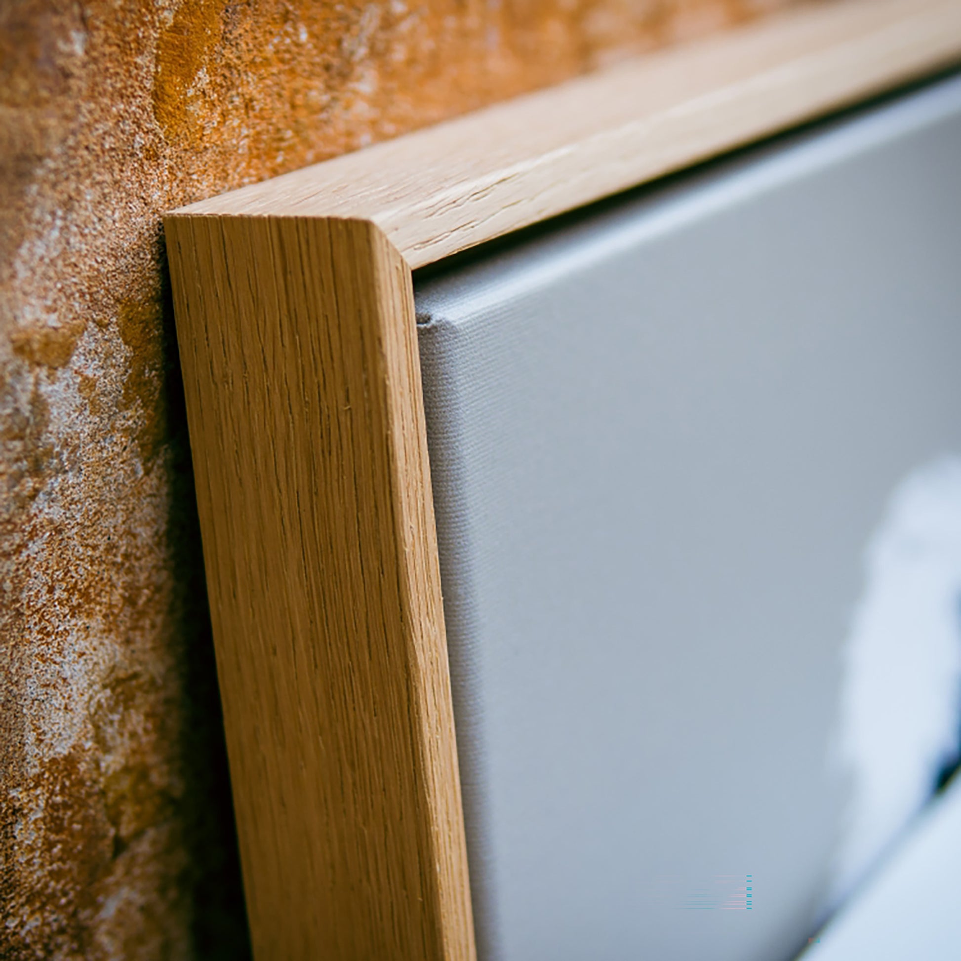 Close-up of a wooden frame corner with a textured wall background