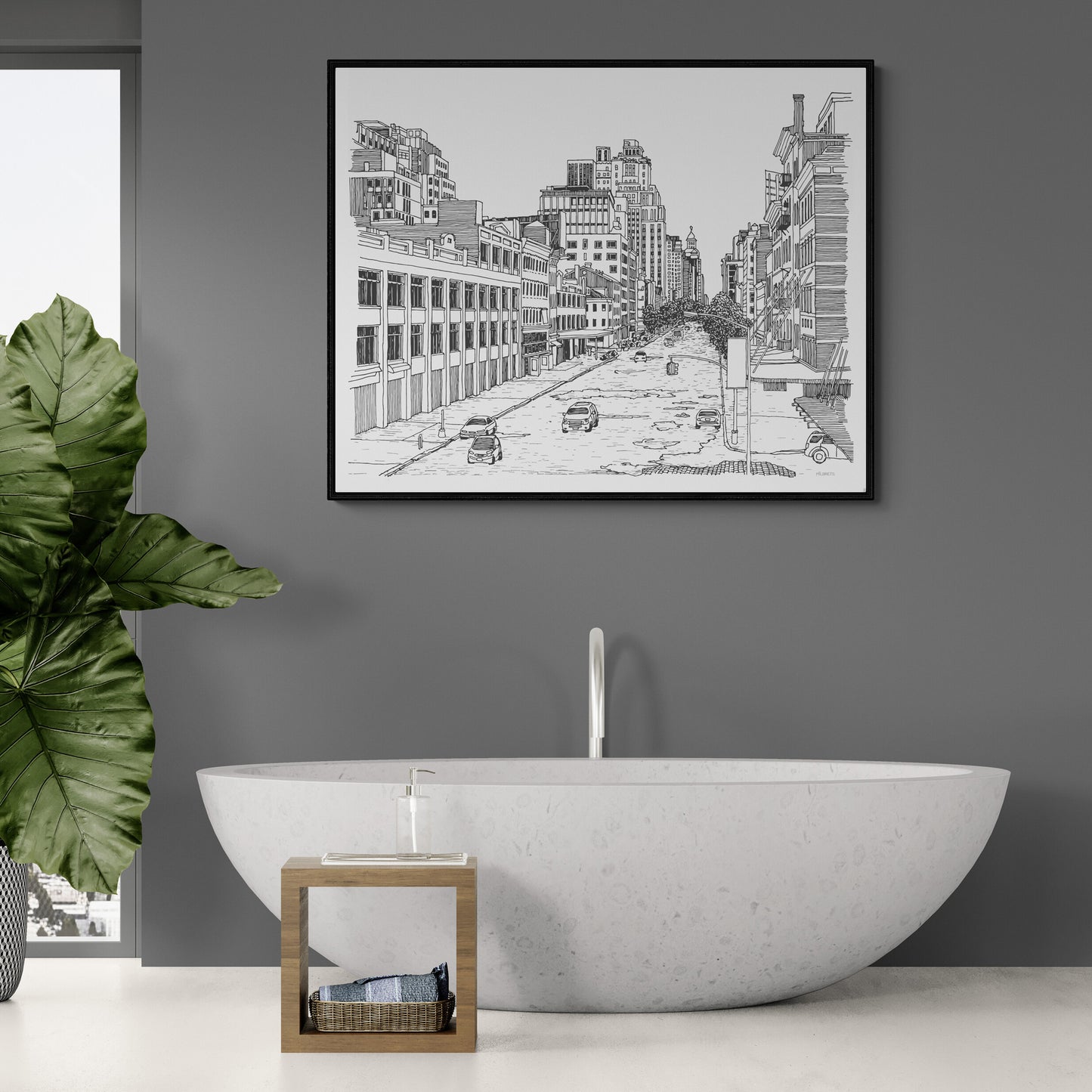 Bathroom interior with a bathtub, framed cityscape art, and a plant.