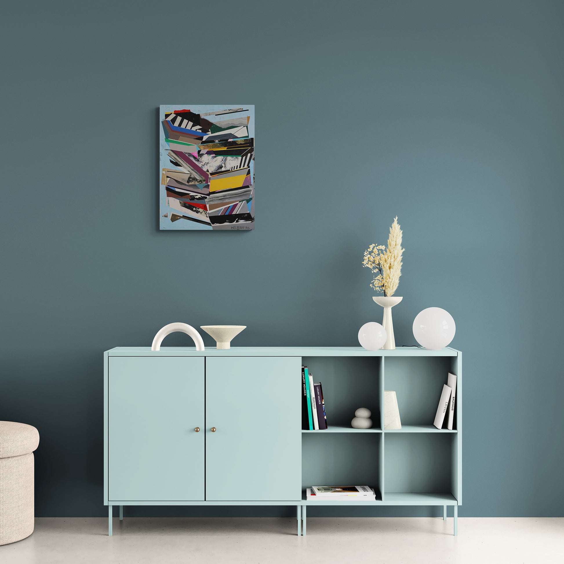 Light blue cabinet with decorative items and original artwork against a dark teal wall