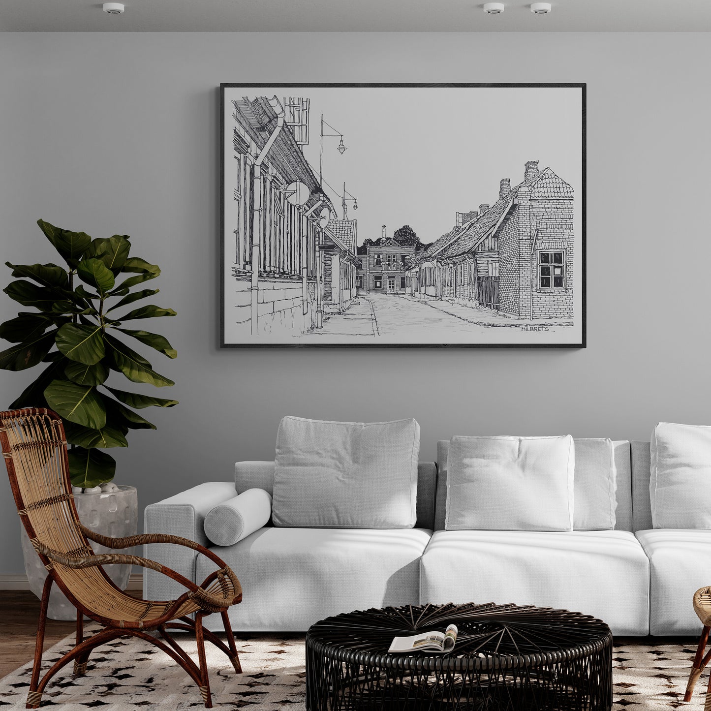 Living room with white sofa, wicker chair, and framed artwork on the wall.