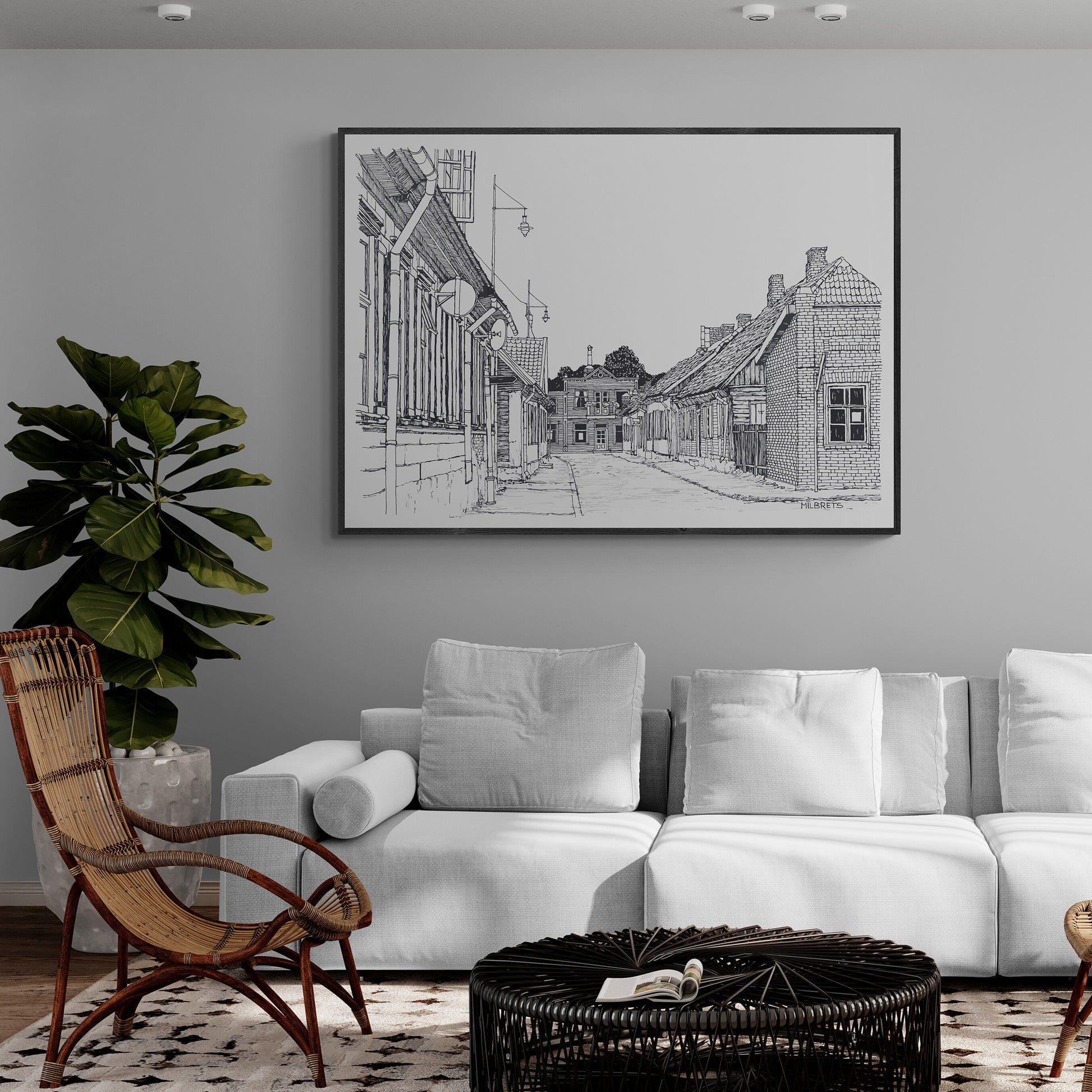 Living room with white sofa, wicker chair, and framed artwork on the wall.