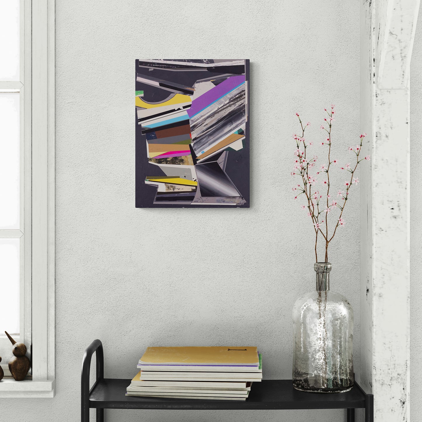 Abstract contemporary art piece on a wall above a table with books and a vase.