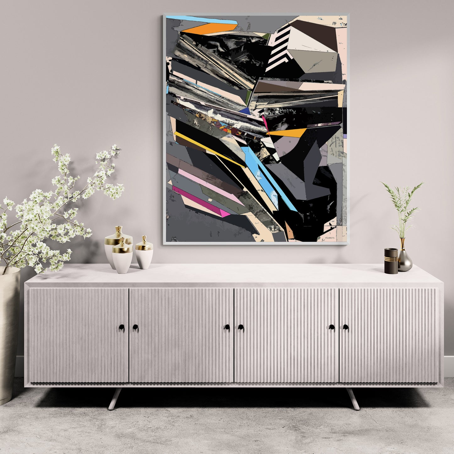A framed abstract geometric wall art print with black, gray, white, blue, and pink shapes, displayed above a light gray ribbed sideboard cabinet in a styled room setting.