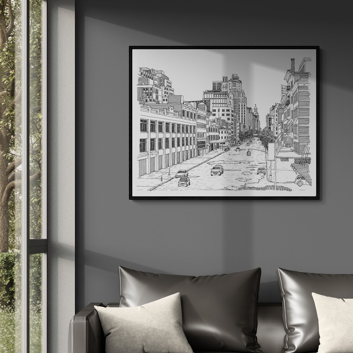Framed black and white cityscape print on a wall above a sofa with cushions.