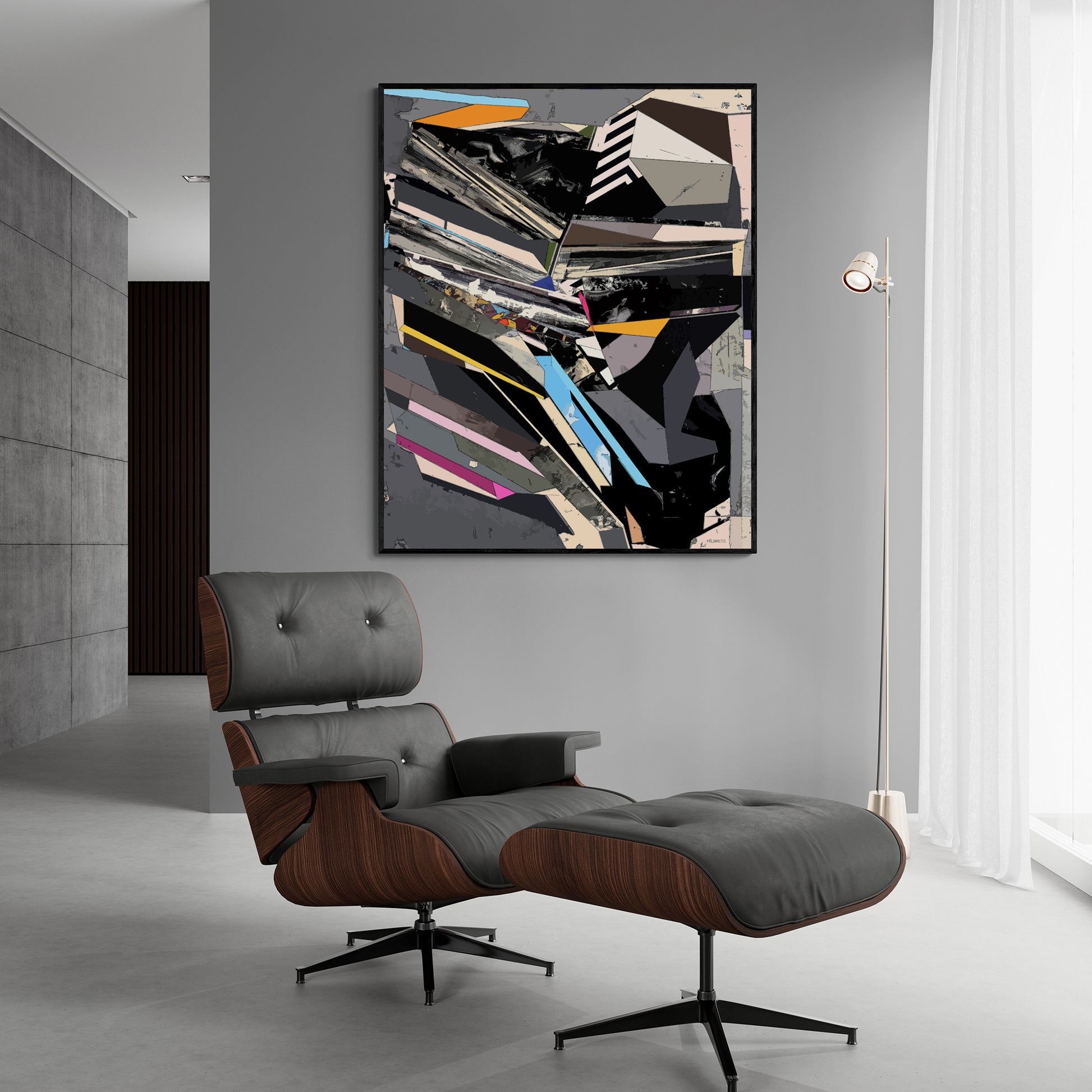 A modern abstract wall art print with black, white, gray, and colorful geometric shapes, displayed in a black frame on a gray wall above a gray leather lounge chair and ottoman.
