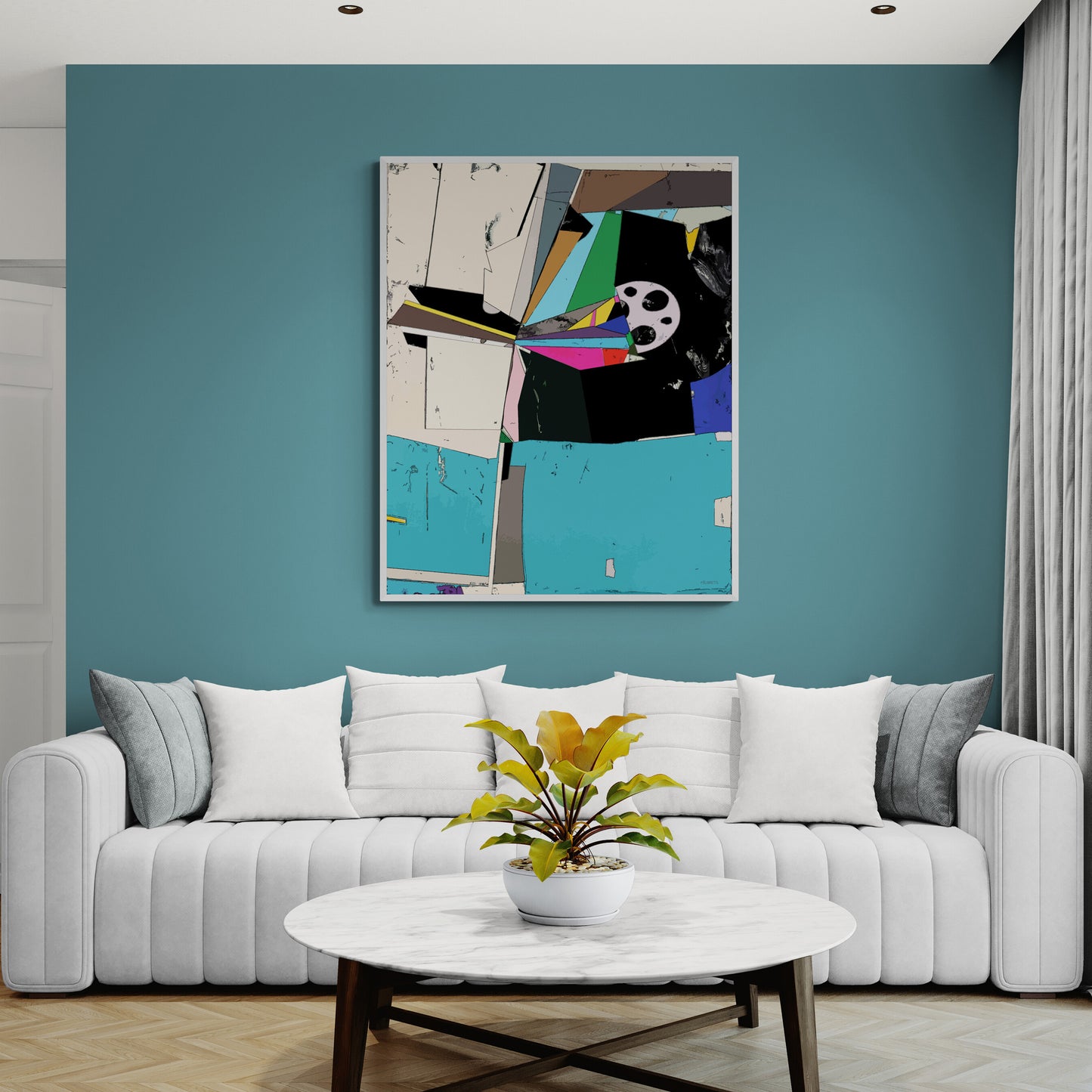 A framed abstract canvas print with geometric shapes in teal, black, white, gray, and bright accents, hanging on a teal wall above a white sofa in a modern living room.