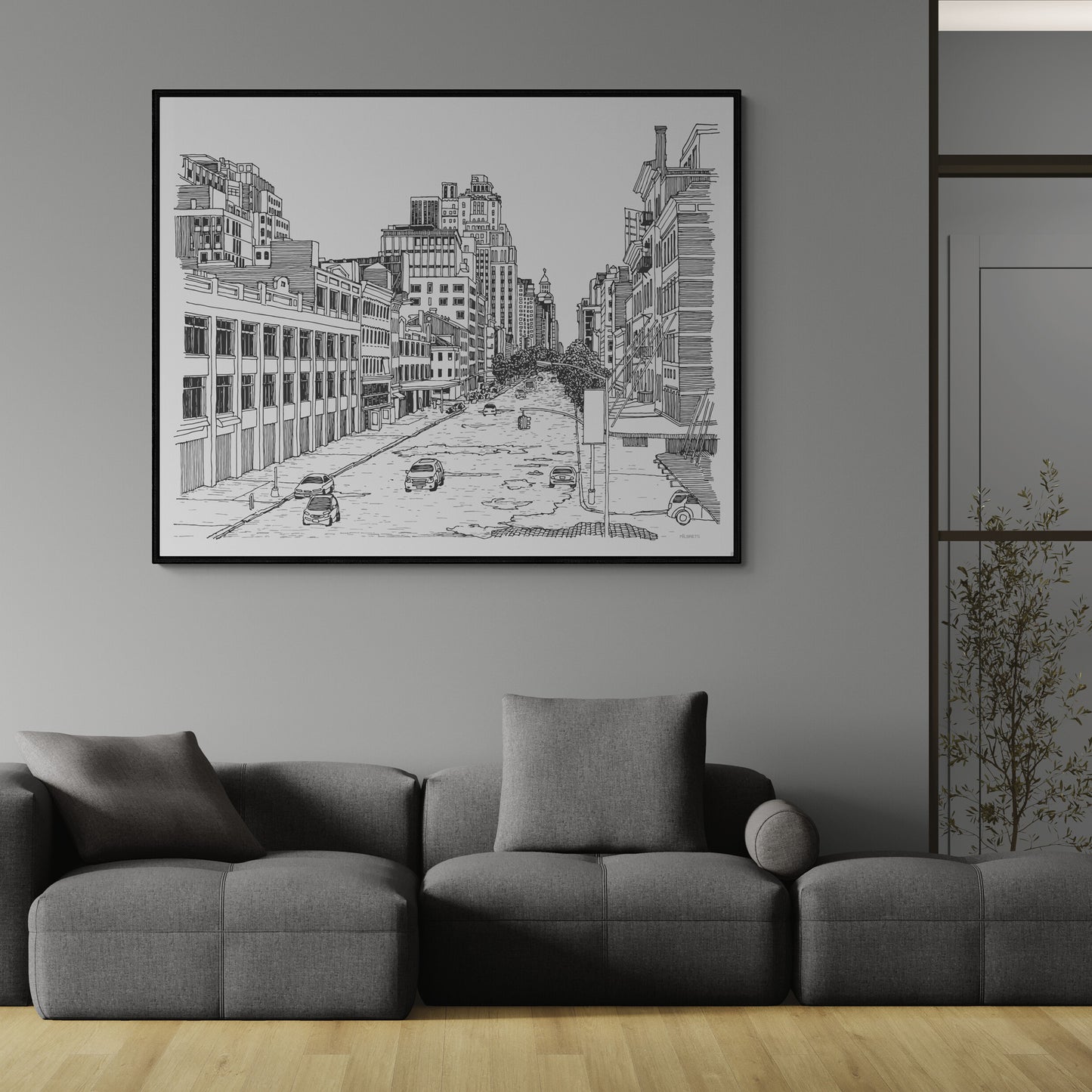 Framed black and white cityscape art on a gray wall above a gray sofa.