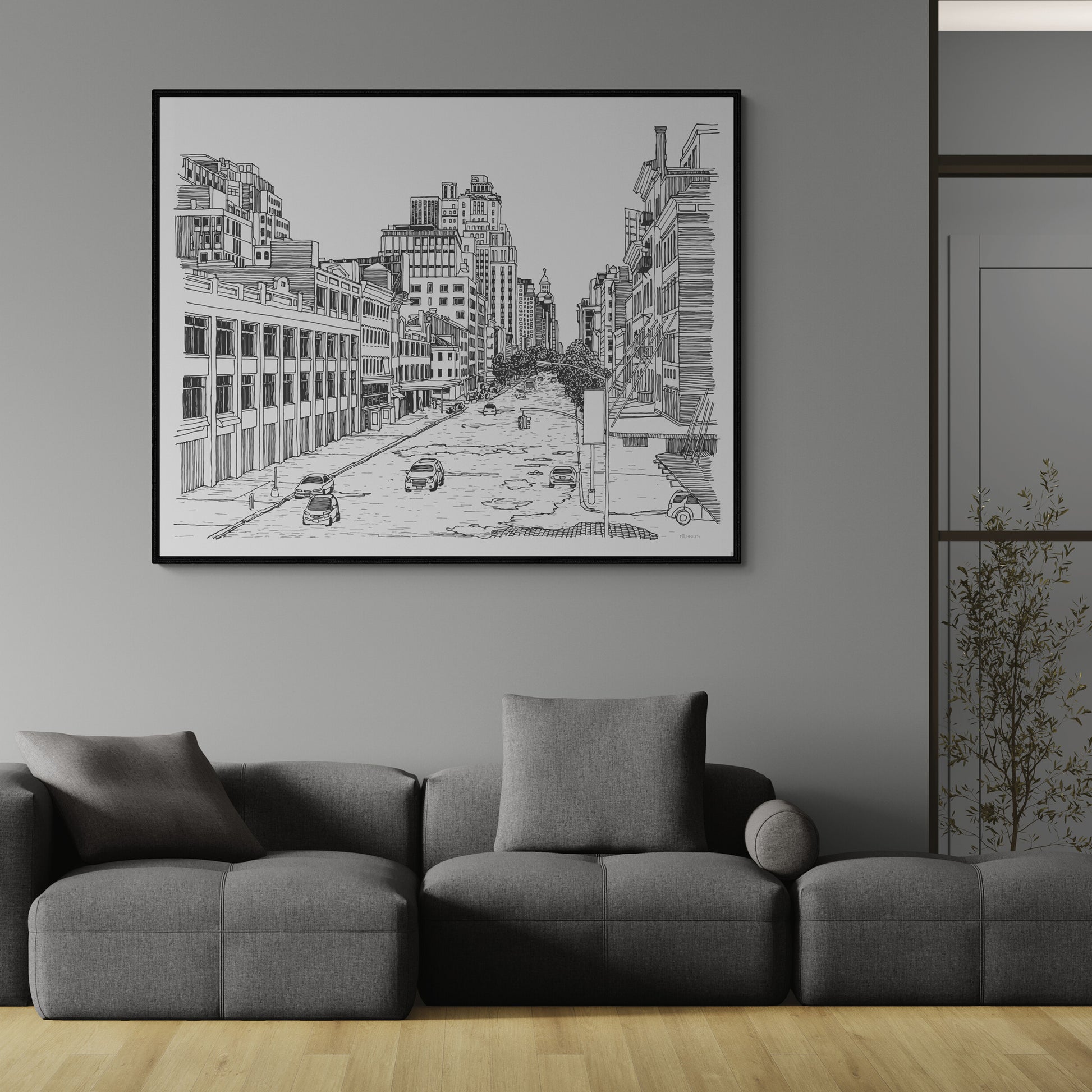 Framed black and white cityscape art on a gray wall above a gray sofa.