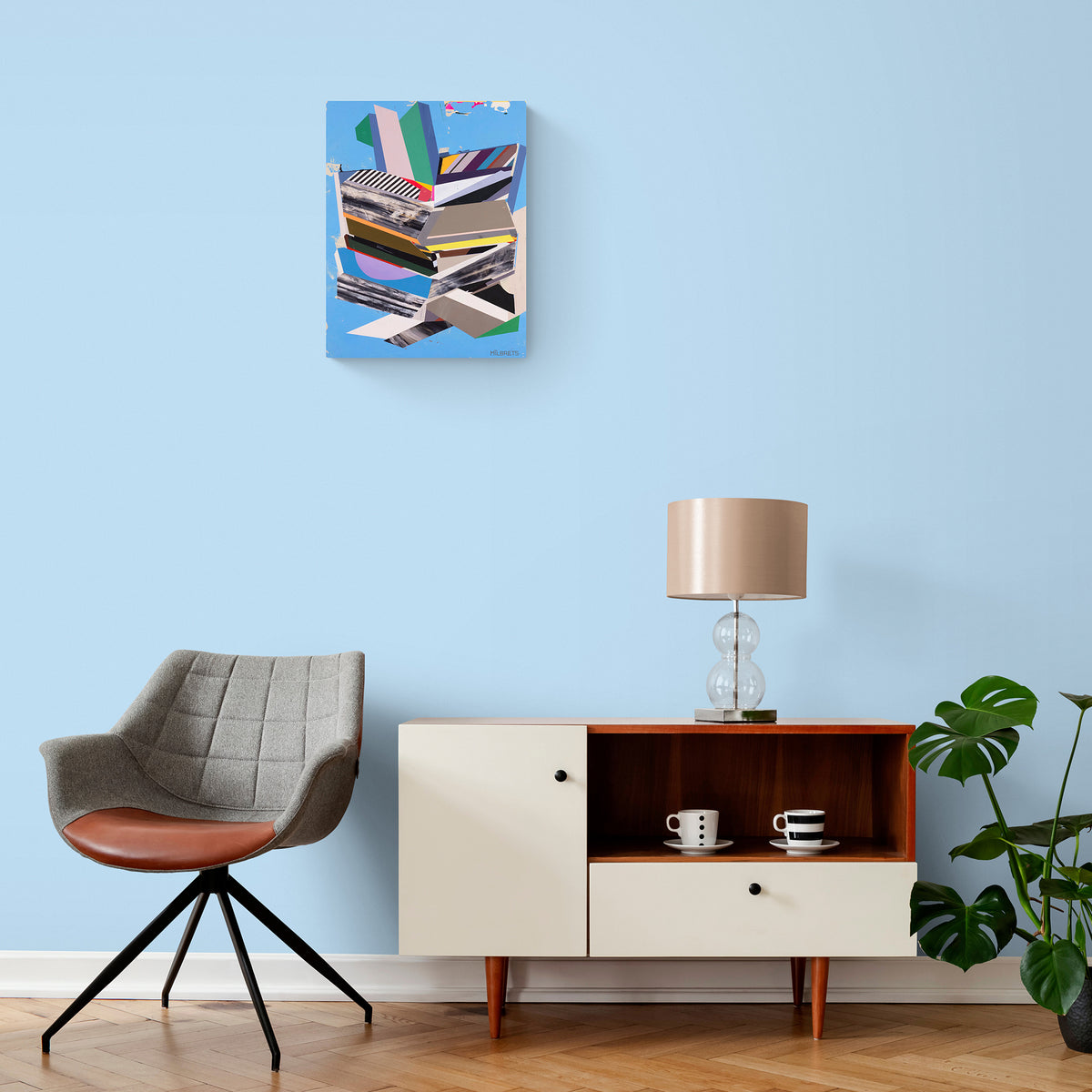 Modern interior with a chair, sideboard, lamp, and plant against a light blue wall with a colorful abstract painting.