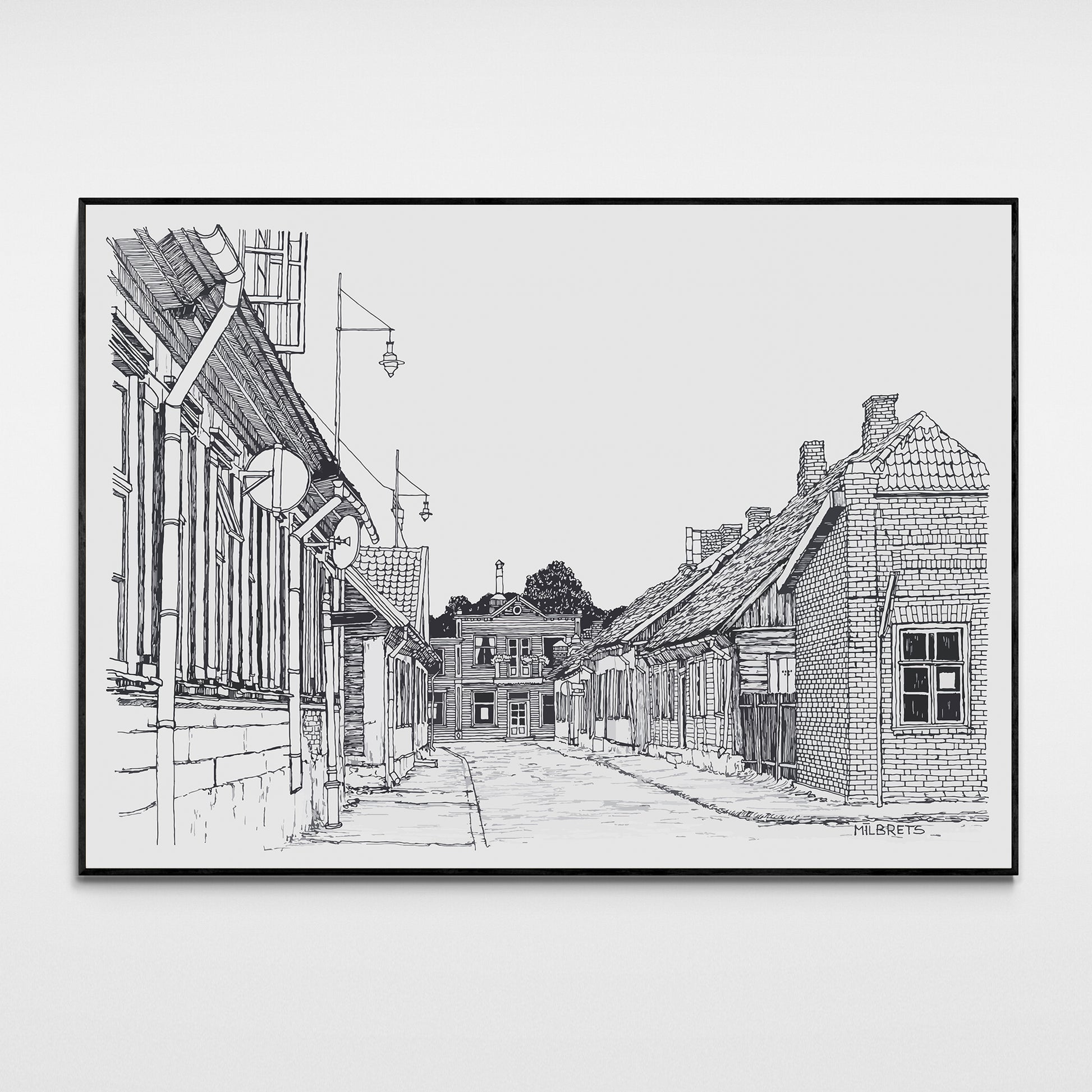Black and white line drawing of a street scene with buildings, framed on a white wall.